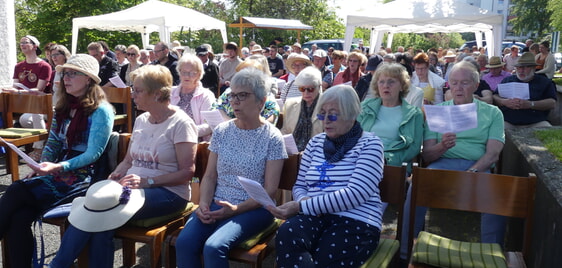 Auftakt der Veranstaltung bildete ein Open-Air-Gottesdienst auf dem Vorplatz der Kirche, auf dem man zum Schutz gegen die Sonne Strohhüte verteilt. (Foto: Ingrid Weiland)