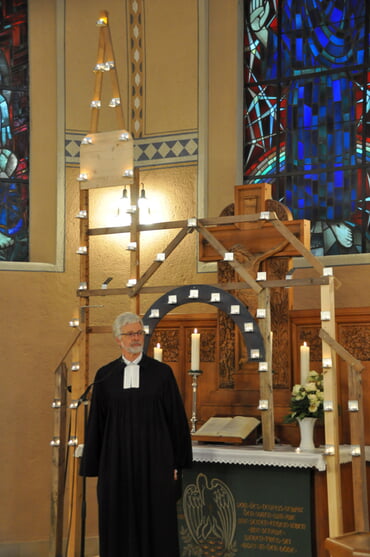 Pfarrer Andreas Schliebener vor der mit Teelichtern geschmückten Silouette der Erlöserkirche (Foto: Ernst)