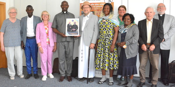 Tauschten beim Empfang im Haus der Ev. Kirche in Lüdenscheid Erfahrungen aus (v.l.n.r): Ursula Büsing, Edison Kyamanywa, Iris Jänicke, Arnold Mudogo, Dr. Christof Grote – hier in Gastgeschenken gekleidet - Georgina Kilezi, Jutta Tripp, Tapita Tuvana, Lothar Sönnecken und Achim Schwarz (Foto: Wolfgang Teipel)