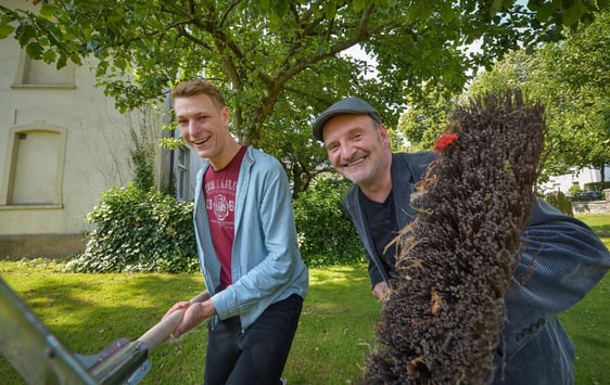 Patrick Schauerte und Guido Raith (v.l.) zeigen, wie es geht: Mit Besen, Schaufel oder Rasenmäher kann es unter freiem Himmel ab sofort wieder losgehen. Die Taschengeldbörse nimmt wieder Anfragen von Senioren an, die sich zum Beispiel Unterstützung bei der Gartenarbeit wünschen.